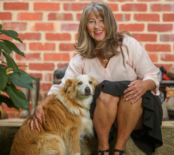 A woman sitting on the ground with her dog.