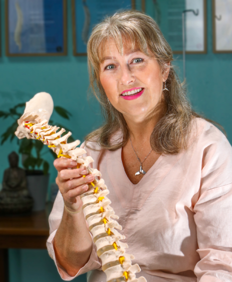 A woman holding up a skeleton model in her hands.