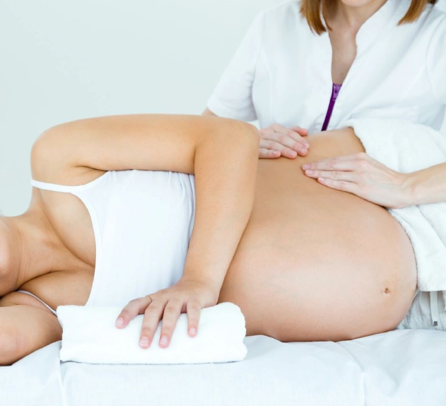 A woman is holding her pregnant belly while another person holds the arm of her.