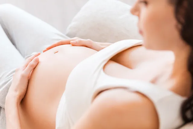 A woman is lying down with her stomach exposed.