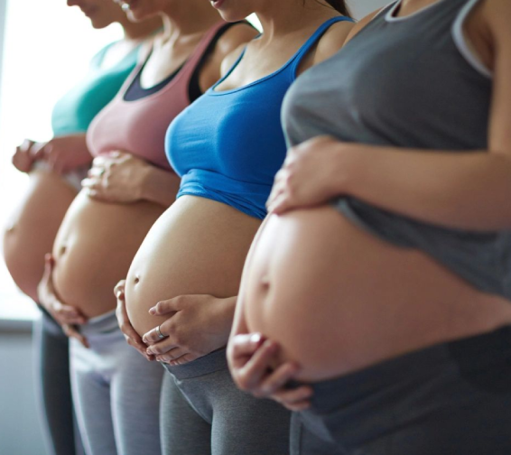 A line of pregnant women standing next to each other.